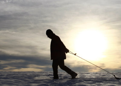 A man trails a child on his sledge during a sunny winter day near Kempten